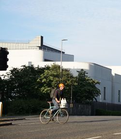 Man riding bicycle on street against buildings in city