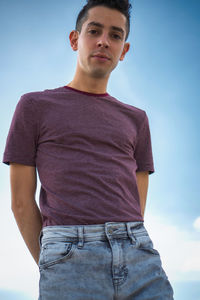 Portrait of young man standing against sky
