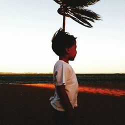 Man standing on beach against sky during sunset