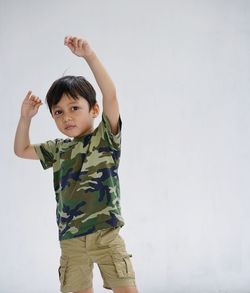 Portrait of cute boy with arms raised dancing against white background