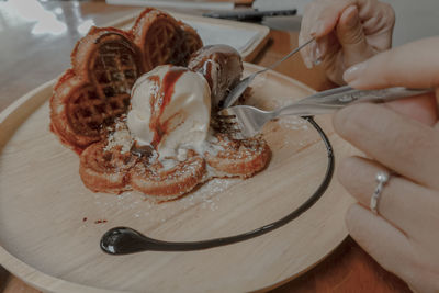 Midsection of person holding ice cream on table