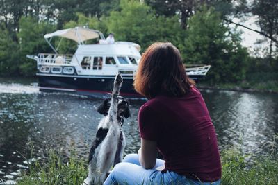 Rear view of woman sitting on boat moored at lakeshore