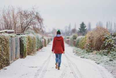 Rear view of woman walking on snow covered footpath