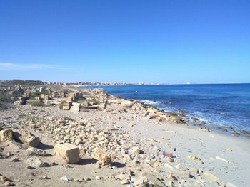 Scenic view of beach against clear blue sky