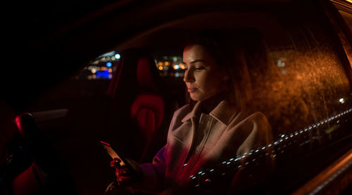 Beautiful businesswoman commuting from office in luxury car at night