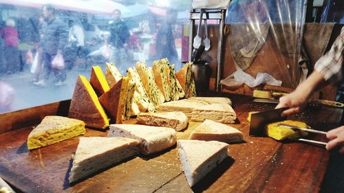 Cropped image of vendor cutting food at market stall