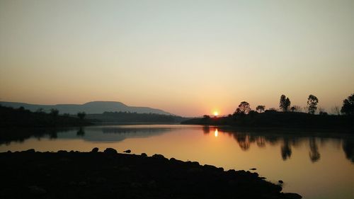 Scenic view of lake against clear sky during sunset