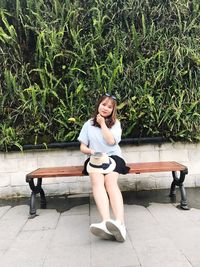 Smiling young woman sitting by plants