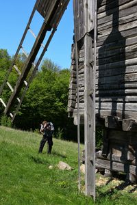 Man photographing wooden traditional windmill at pyrohiv on sunny day