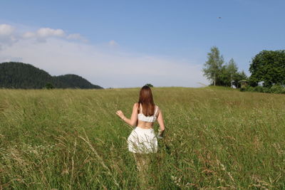 Rear view of woman standing on field against sky