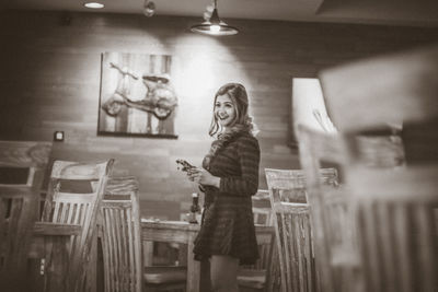 Portrait of smiling young woman standing against wall