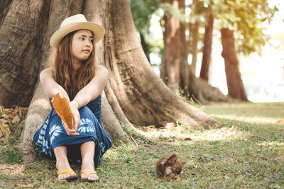 Woman sitting with dog on grassy field