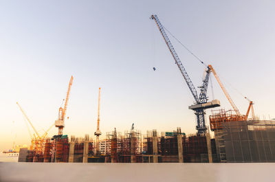 Cranes at construction site in city against clear sky