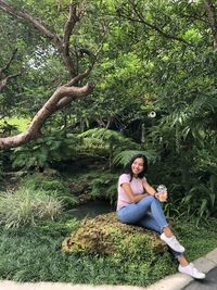 Full length of young woman sitting on land