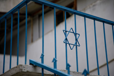 Close-up of metal fence against blue wall