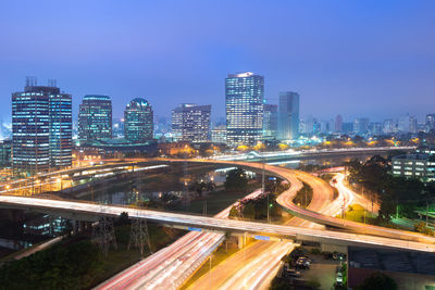 High angle view of light trails on road by buildings against sky