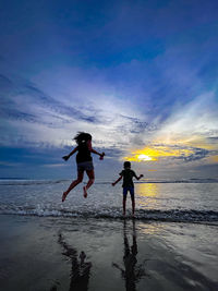 Rear view of woman standing at beach against sky