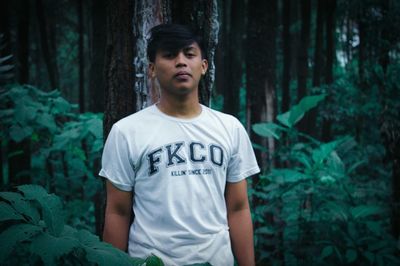Young man looking away in forest
