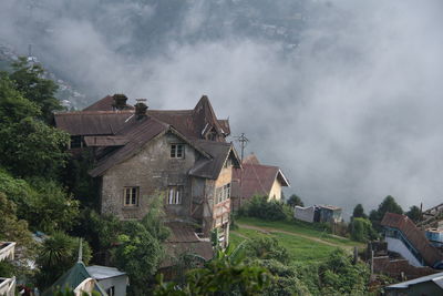 Houses by buildings in town against sky