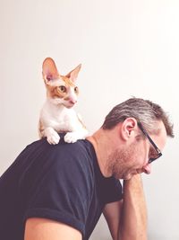 Portrait of young man with cat against white background