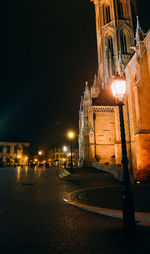 Illuminated street light in city against sky at night