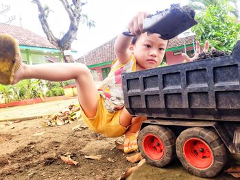 Cute girl playing with toy car on land