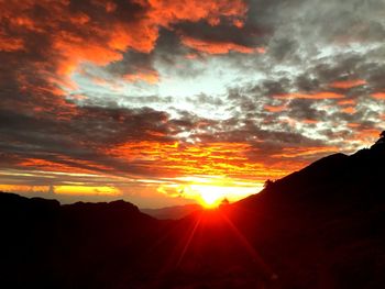 Scenic view of silhouette mountains against orange sky