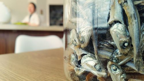 Close-up of dried sardines in container on table at restaurant