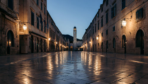 Street amidst buildings in city at dusk