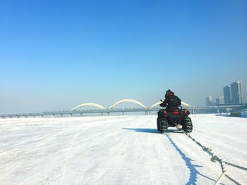 Quadbike on snowy field against clear blue sky during sunny day