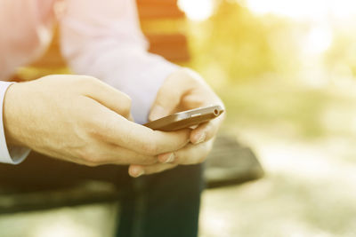 Midsection of person holding mobile phone outdoors