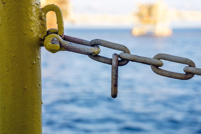 Close-up of chain on railing against sea