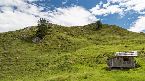 Chalet on green mountain against sky