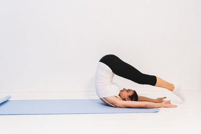 Young woman in yoga class doing shoulder stand