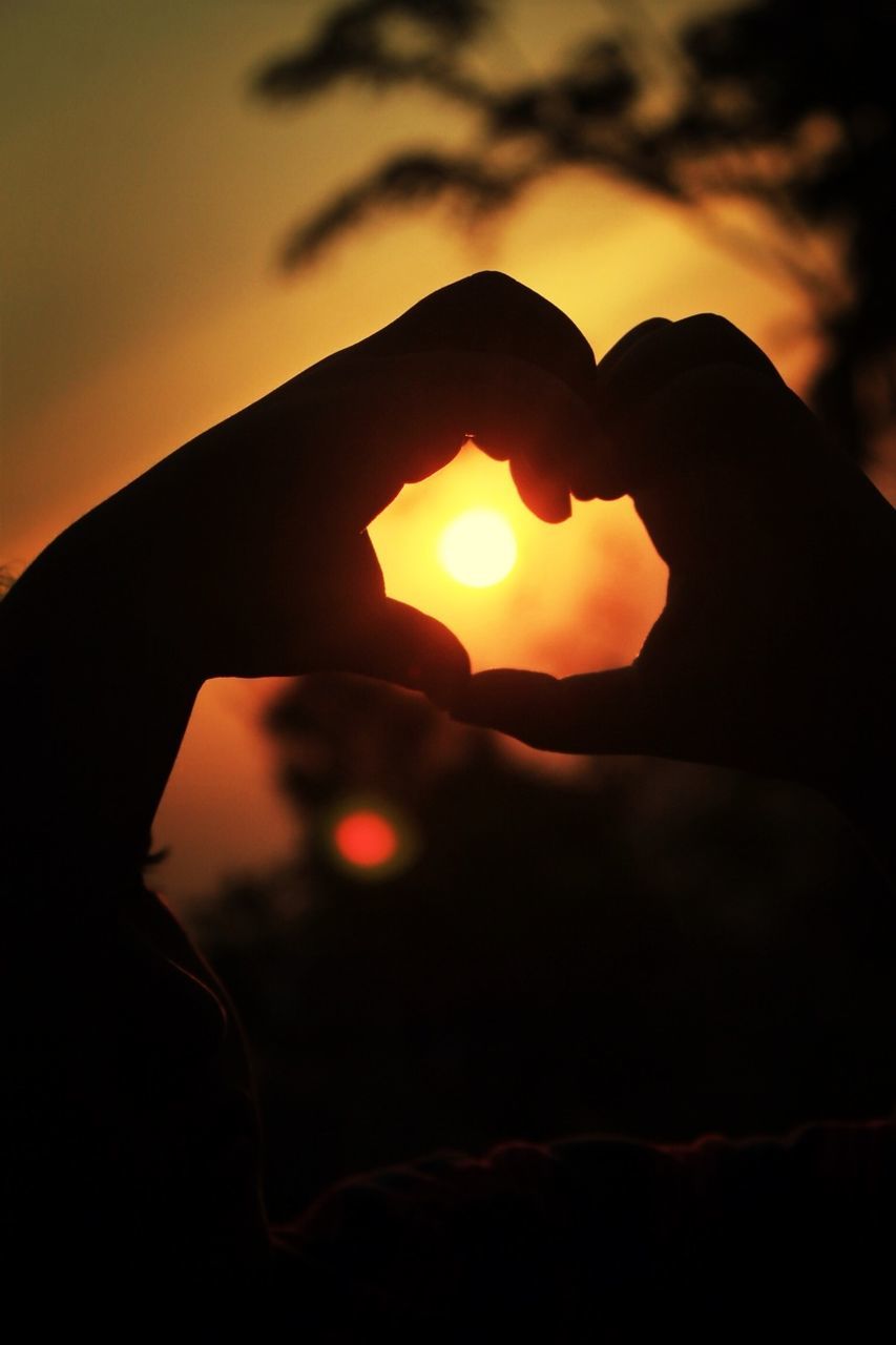 sunset, sun, silhouette, orange color, sky, one person, back lit, sunlight, close-up, tranquility, beauty in nature, nature, part of, scenics, outdoors, person, reflection, tranquil scene, sunbeam, focus on foreground