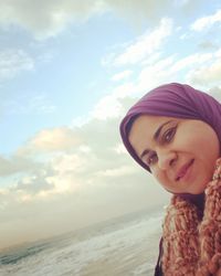 Portrait of smiling young woman on beach against sky