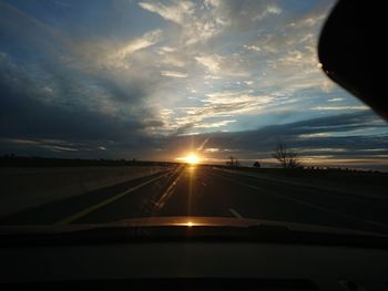 Road seen through car windshield during sunset