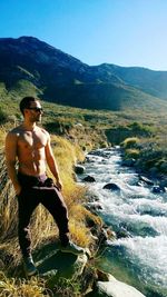 High angle view of shirtless man sitting on mountain against sky