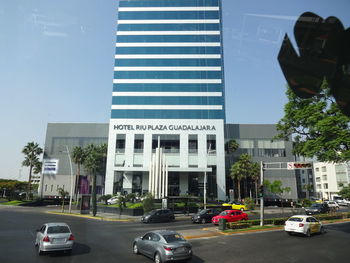 Cars on road by buildings in city against sky