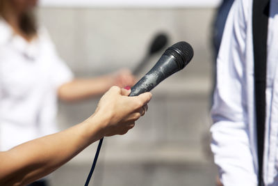 Cropped hand of journalist holding microphone for man