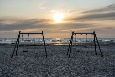 Lifeguard hut on beach against sky during sunset