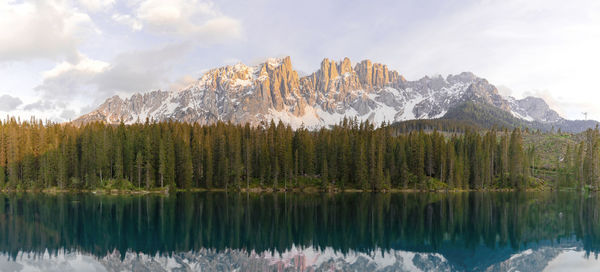 Beautiful view of lake in front of pine forest and mountains at sunset