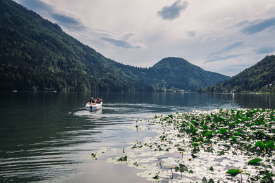 People in boat on lake against sky