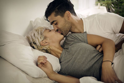 Young couple kissing on bed at home