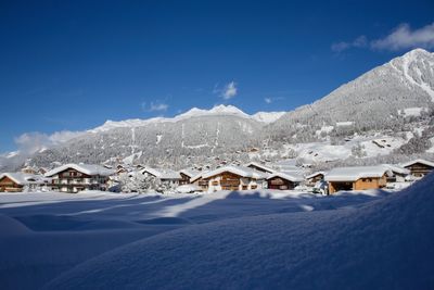 Houses on snowcapped mountain against blue sky