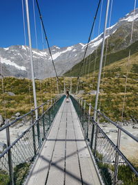 Man on footbridge over mountain against sky