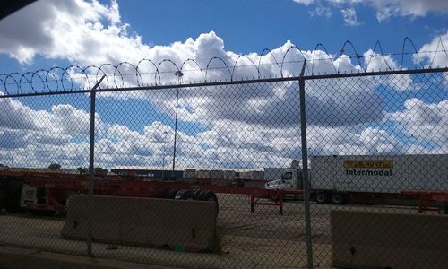 Chainlink fence against sky in city