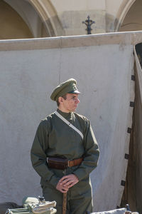 Man holding camera while standing against built structure