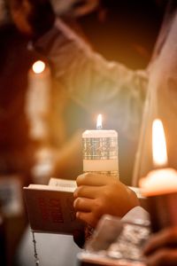 Close-up of hand holding lit candles