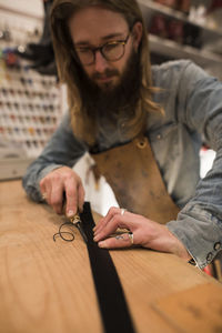 Shoemaker cutting leather on workbench at workshop